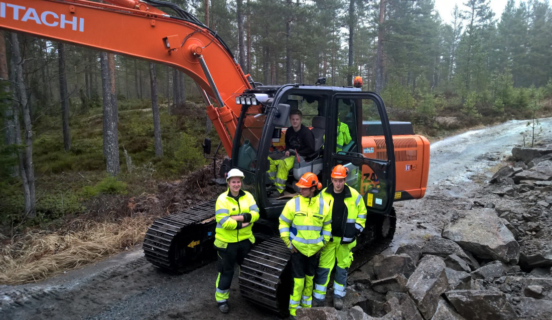 PRAKSIS: Her er den nye klassen ute i skogen og får praksis på maskinkjøring. Fra venstre: Martine B. Bratsberg, Henrik Rønningen og Erik L. Jørgensen. Steffen Haugerød sitter i gravemaskinen.
