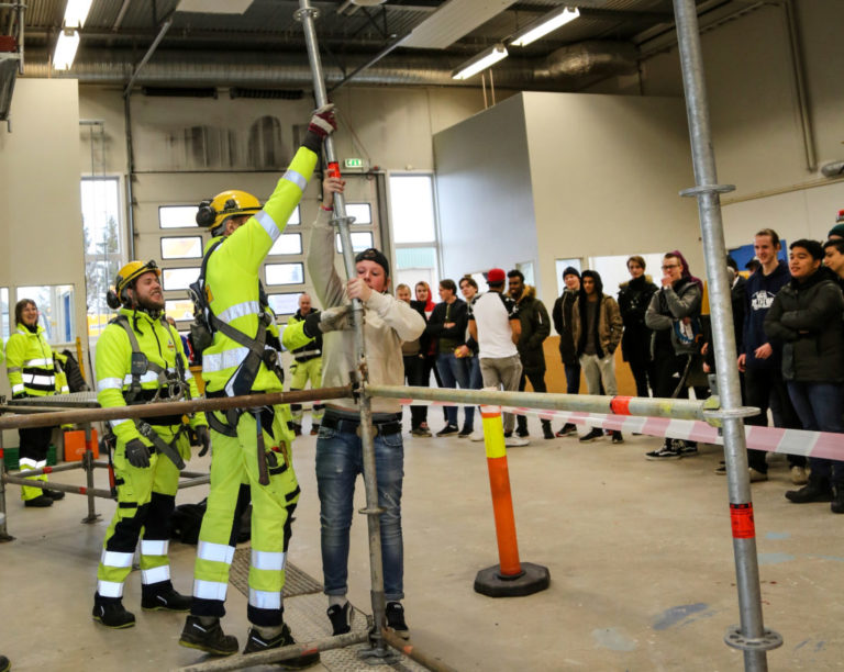 TUNGT: Elevene fikk også prøve litt enkel stillasbygging, og stengene var tyngre enn de trodde. Her er det Johannes Saxegård (16) fra Greåker vgs. som må ha litt kyndig hjelp for å beholde kontrollen. (Foto: Runar F. Daler).