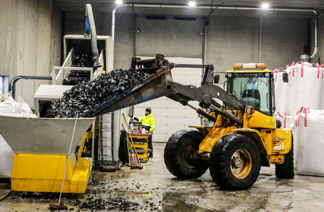 VIDUNDERMASKIN: Hjullasteren heller grovkvernede plastrør på samlebåndet. I den andre enden fyker det ut små plastkuler – granulatet – som automatisk blir lastet opp i store sekker. (Foto: Runar F. Daler).