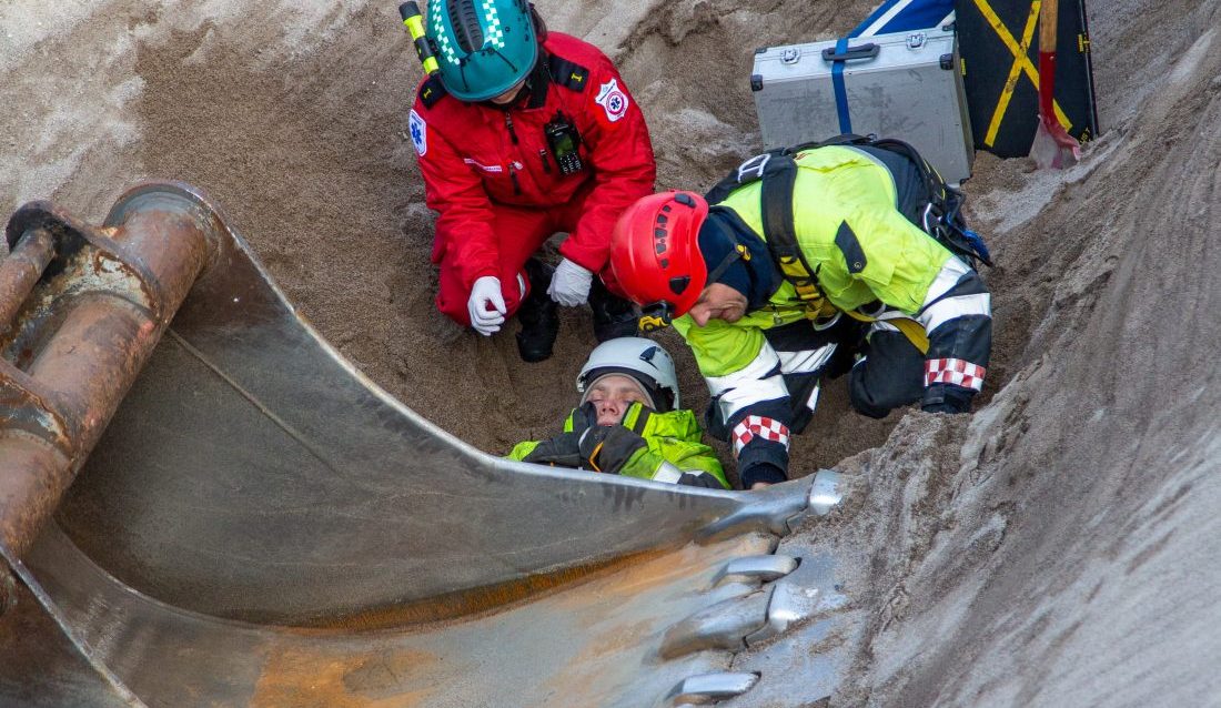Det er ikke hyggelig å se en anleggsarbeider liggende i klem under en skuffe. Heldigvis er det bare en øvelse. (Foto: Runar F. Daler)