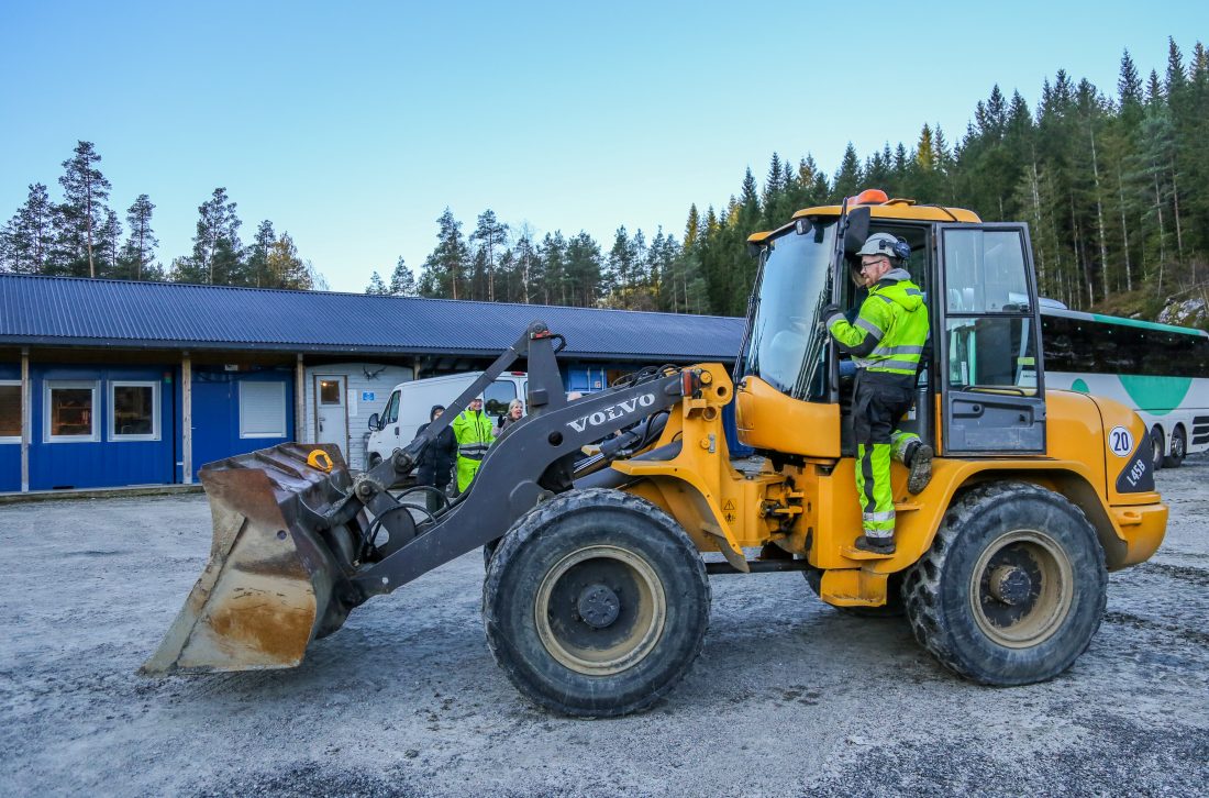 Delegasjonen lot seg begeistre av de ulike maskinene som elevene har til rådighet. Her er det anleggsteknikklærer Lars Petter Sneve som veileder en av de besøkende som ville prøve hjullasteren. (Foto: Runar F. Daler)