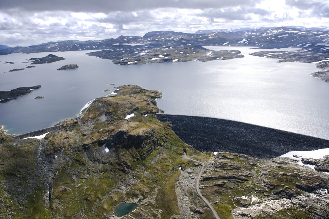 En 650 meter lang steinfyllingsdam demmer opp Nyhellermagasinet, i dag. Nå skal dammen forsterkes med om lag 400 000 m3 steinmasser. (Foto: Veidekke)