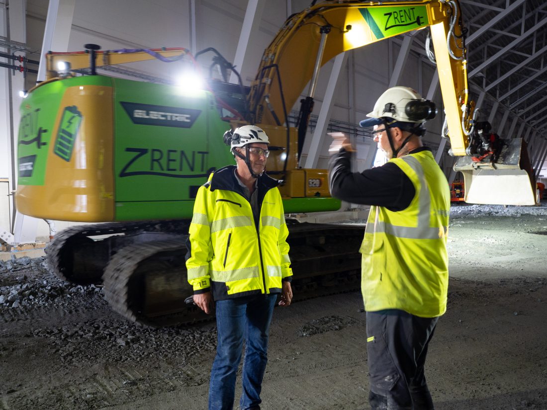 Prosjektleder Svein Skottvoll følger godt med når Leif Otto Fischer snakker om fremdriften. I bakgrunnen ser vi den elektriske gravemaskinen selskapet bruker i hallen.