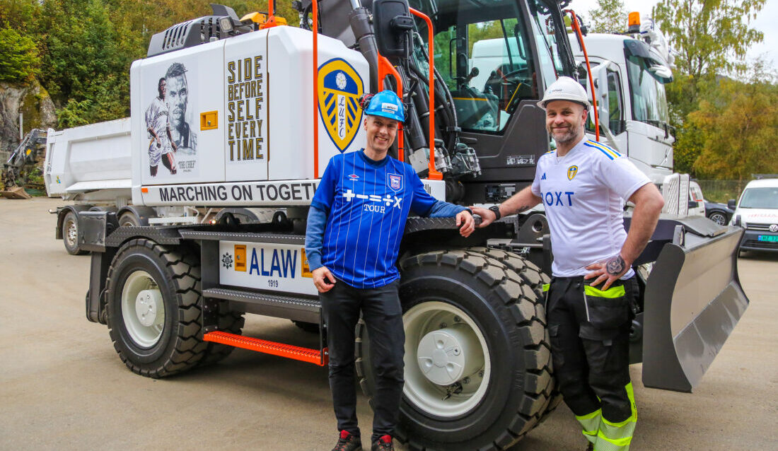 STOR DAG: En smørblid maskinfører Øystein Lauritsen (t.h.) ved Envirs anlegg på Laksevåg i Bergen, har her akkurat fått en splitter ny Volvo-hjulgraver dekortert med sitt favorittlag Leeds United. Legg også merke til tatoveringen på hånda hans. Sjefen hans, Kolbjørn Akervold, som selv er Ipswich-supporter, er også fornøyd. (Foto: Runar F. Daler)